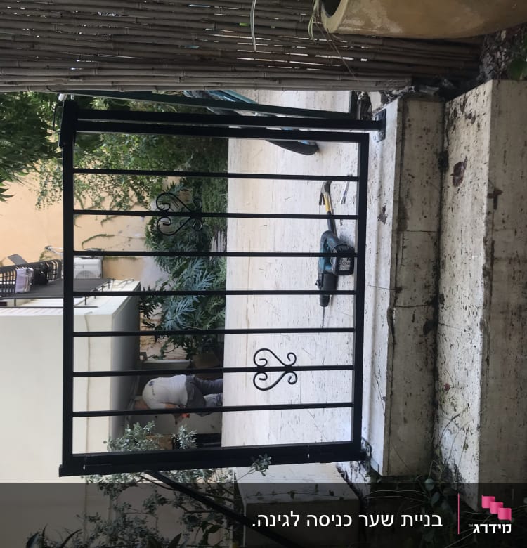 שער מתכת שחור עם עיטורים על מדרגות אבן